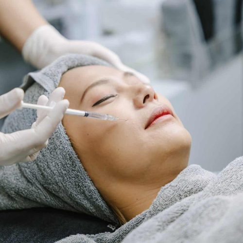 Beautician skin doctor injecting filler at woman face skin for facial treatment in beauty clinic