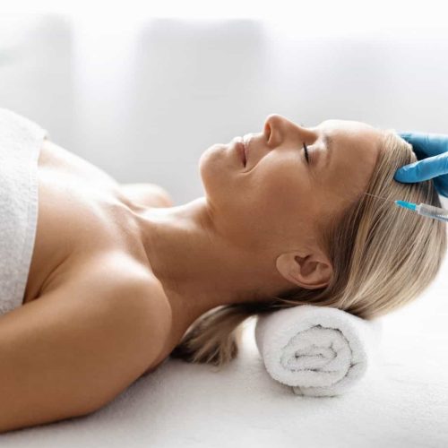 Beautiful middle aged woman getting hair treatment at beauty salon