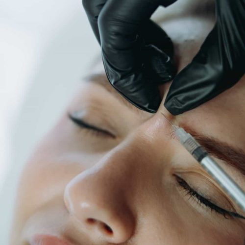 close up of professional hands making Botox ingection into woman frown line